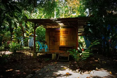 a wooden shelter with a blue chair in a garden at Flutterby House Hostel in Uvita