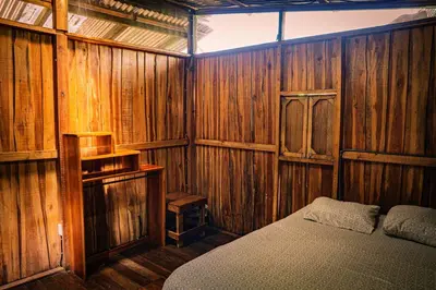a bedroom with wooden walls and a bed in it at Flutterby House Hostel in Uvita