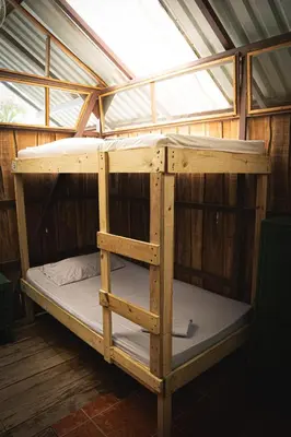 a wooden bunk bed in a room with a window at Flutterby House Hostel in Uvita