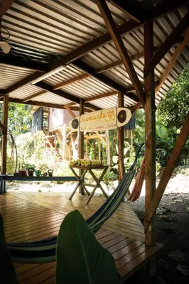 a hammock on a wooden deck with a table at Flutterby House Hostel in Uvita