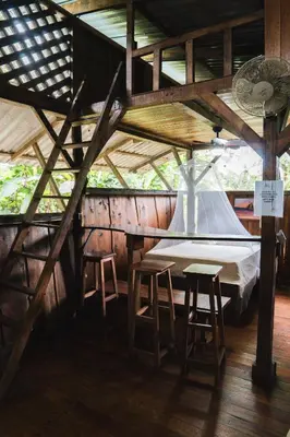 a bedroom with a bed and stools in a room at Flutterby House Hostel in Uvita