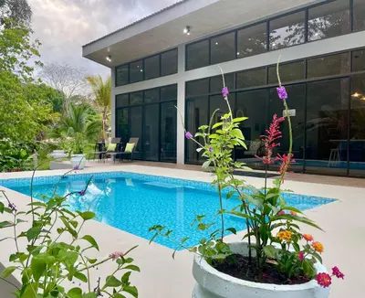 a swimming pool in front of a house at An abundance of wildlife at Jungle Glory Home Abajo in Manuel Antonio