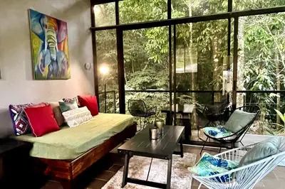 a room with a bed and chairs and a window at An abundance of wildlife at Jungle Glory Home Abajo in Manuel Antonio