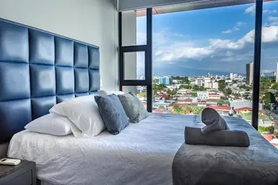 a bedroom with a large bed with a large window at Rooftop and city view Aparment in San José