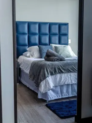 a mirror reflecting a bed with a blue headboard and pillows at Rooftop and city view Aparment in San José