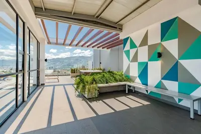 a balcony with a bench and a geometric wall at Rooftop and city view Aparment in San José