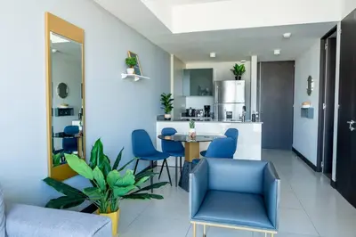 a kitchen and living room with blue chairs and a table at Rooftop and city view Aparment in San José