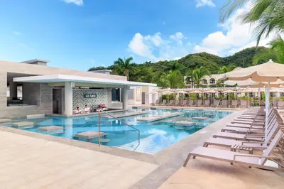 a pool at a resort with chairs and umbrellas at Riu Guanacaste - All Inclusive in Coco