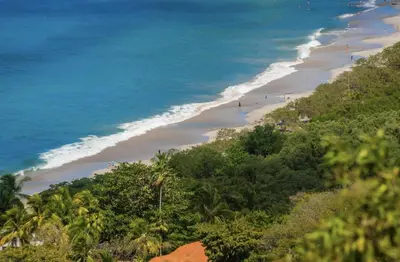 a beach with people walking on the sand and the ocean at Casa Del Mar - 4 Br House In Flamingo in Playa Flamingo