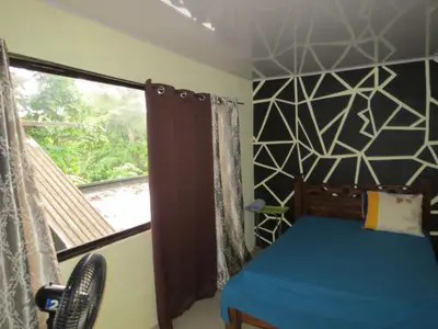 a bedroom with a blue bed and a window at House la Rose Second Floor in Manuel Antonio