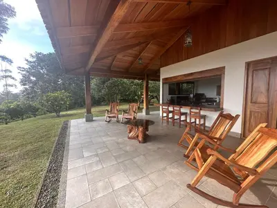 a patio with wooden chairs and a table and a television at Casa areno lodge in Bijagua