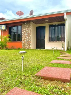 a house with a green yard with a building at Casa Heliconia- La Fortuna in Fortuna