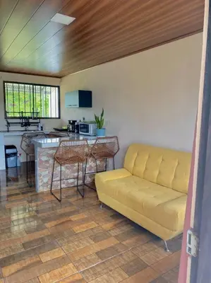 a living room with a couch and a kitchen at Casa Heliconia- La Fortuna in Fortuna