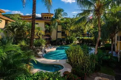 a resort with a swimming pool and palm trees at Beautiful newly refurbished 2 bedroom 2 Bathroom 2nd floor condo in Tamarindo