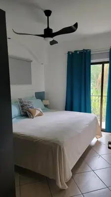a bedroom with a bed with blue curtains and a ceiling fan at Beautiful newly refurbished 2 bedroom 2 Bathroom 2nd floor condo in Tamarindo