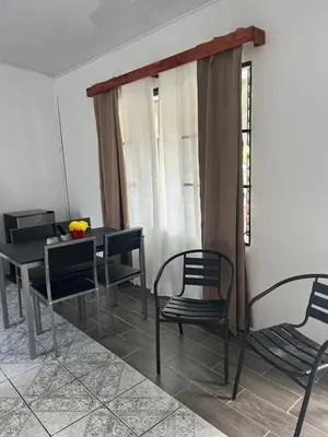a dining room with chairs and a table and a window at Buganvilla No 4 Aire acondicionado in Quepos