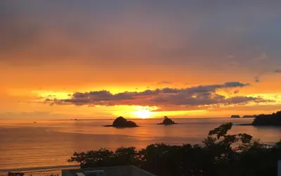 a sunset over the ocean with rocks in the water at Casa Calle La Ronda At Las Catalinas in Playa Danta