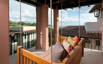 a porch swing with pillows on a balcony at Casa Calle La Ronda At Las Catalinas in Playa Danta