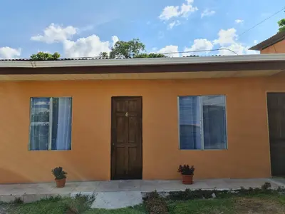a small yellow house with a wooden door at Cabinas Guayabón #4, AC, La Fortuna Volcán Arenal in Fortuna