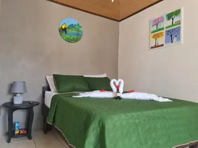 a bedroom with a green bed with a stuffed bunny on it at Cabinas Guayabón #4, AC, La Fortuna Volcán Arenal in Fortuna