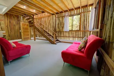 a living room with two red chairs and a staircase at Sámara Tarantela Houses, Casa Bambú in Sámara