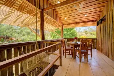 a wooden porch with a table and chairs on it at Sámara Tarantela Houses, Casa Bambú in Sámara