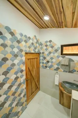 a bathroom with a sink and a wooden door at Sámara Tarantela Houses, Casa Bambú in Sámara