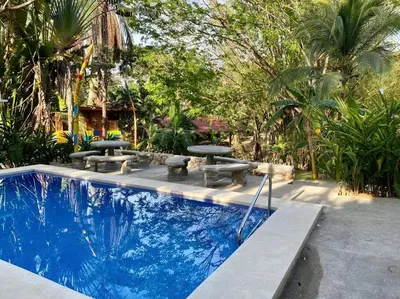 a swimming pool with picnic tables and benches in a yard at Sámara Tarantela Houses, Casa Guadua in Sámara