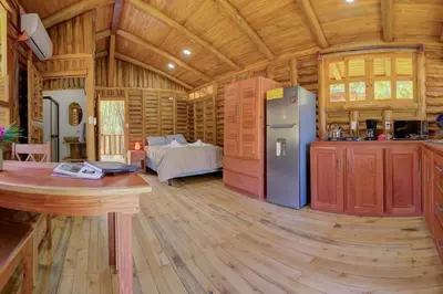 a kitchen and living room of a log cabin at Sámara Tarantela Houses, Casa Sandal in Sámara