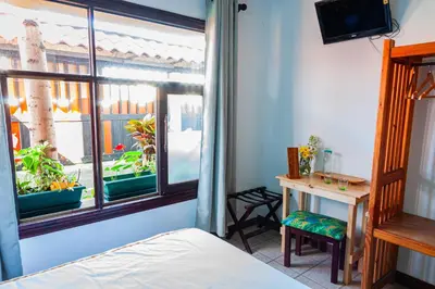 a bedroom with a bed and a desk and a window at Posada Nena Santa Ana in Santa Ana