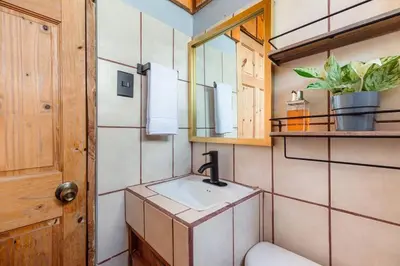 a bathroom with a sink and a toilet and a mirror at The Red Door Mountain Cabin in Guadalupe