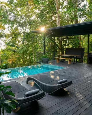 a deck with chaise lounges next to a swimming pool at Casa Alba - Portasol Vacation in Savegre