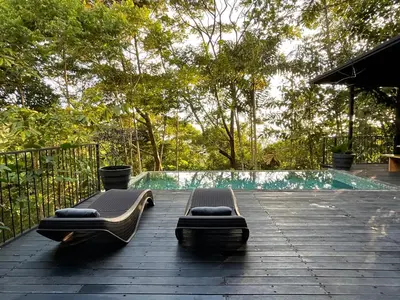 two beds on a deck next to a swimming pool at Casa Alba - Portasol Vacation in Savegre