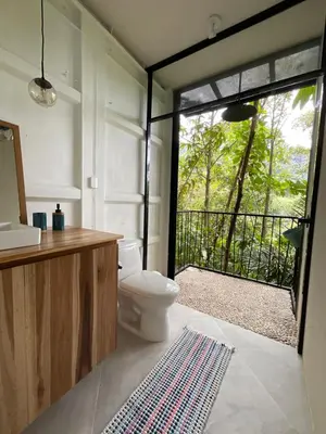 a bathroom with a toilet and a large window at Casa Alba - Portasol Vacation in Savegre