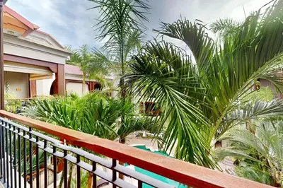 a house with palm trees in front of a fence at Macaw Oceans Club#20 in Jacó