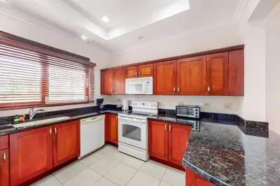 a kitchen with wooden cabinets and white appliances at Macaw Oceans Club#20 in Jacó