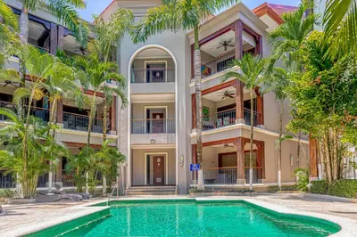 an apartment building with a swimming pool and palm trees at Macaw Oceans Club#20 in Jacó