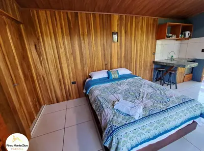 a bedroom with a bed in a wooden wall at Cabaña Montezion Bijagua in Bijagua