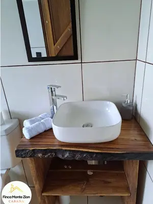 a white sink on a wooden counter in a bathroom at Cabaña Montezion Bijagua in Bijagua