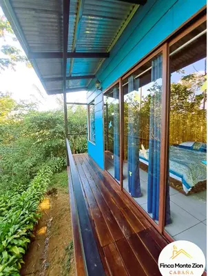 a porch of a house with a bed and windows at Cabaña Montezion Bijagua in Bijagua