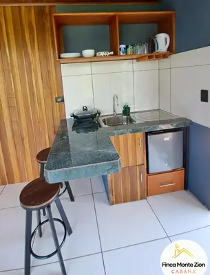 a kitchen with a counter and a sink and a stool at Cabaña Montezion Bijagua in Bijagua