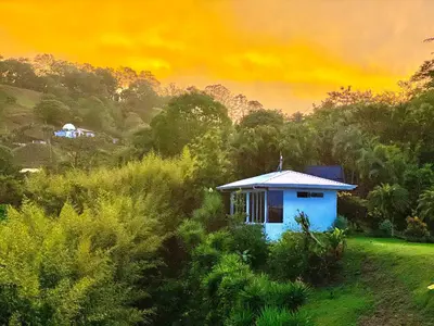 a small blue house in the middle of a field at Cottage in Magic Mountain Views in Barrio Jesús