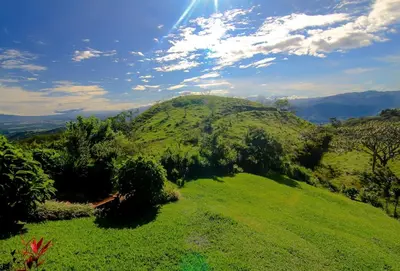 a green hill with the sun shining on it at Cottage in Magic Mountain Views in Barrio Jesús